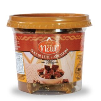 Pote plástico transparente de 300g do Doce de Leite com Amendoim em pedaços da Nhá Nair. O rótulo tem uma faixa principal em marrom avermelhado. A imagem central mostra pedacinhos de doce misturados com amendoim, com uma textura mais rústica e crocante.