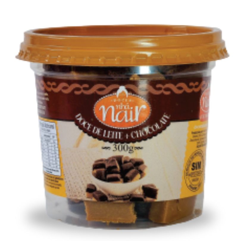 Pote plástico transparente de 300g do Doce de Leite com Chocolate em pedaços da Nhá Nair. O rótulo possui uma faixa principal em marrom escuro. A imagem no centro ilustra cubos do doce em que é visível a cobertura ou a mescla com chocolate escuro.